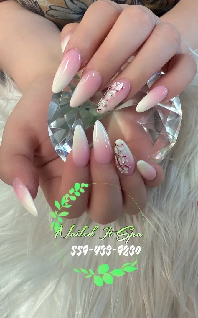 Long almond nails in a pink-to-white ombre with hand-painted cherry blossom accent nails